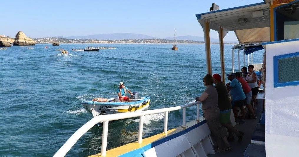 View from a passenger boat towards a smaller boat and rock formations