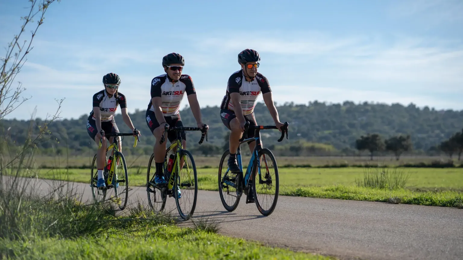Three road cyclists riding side by side along a country road