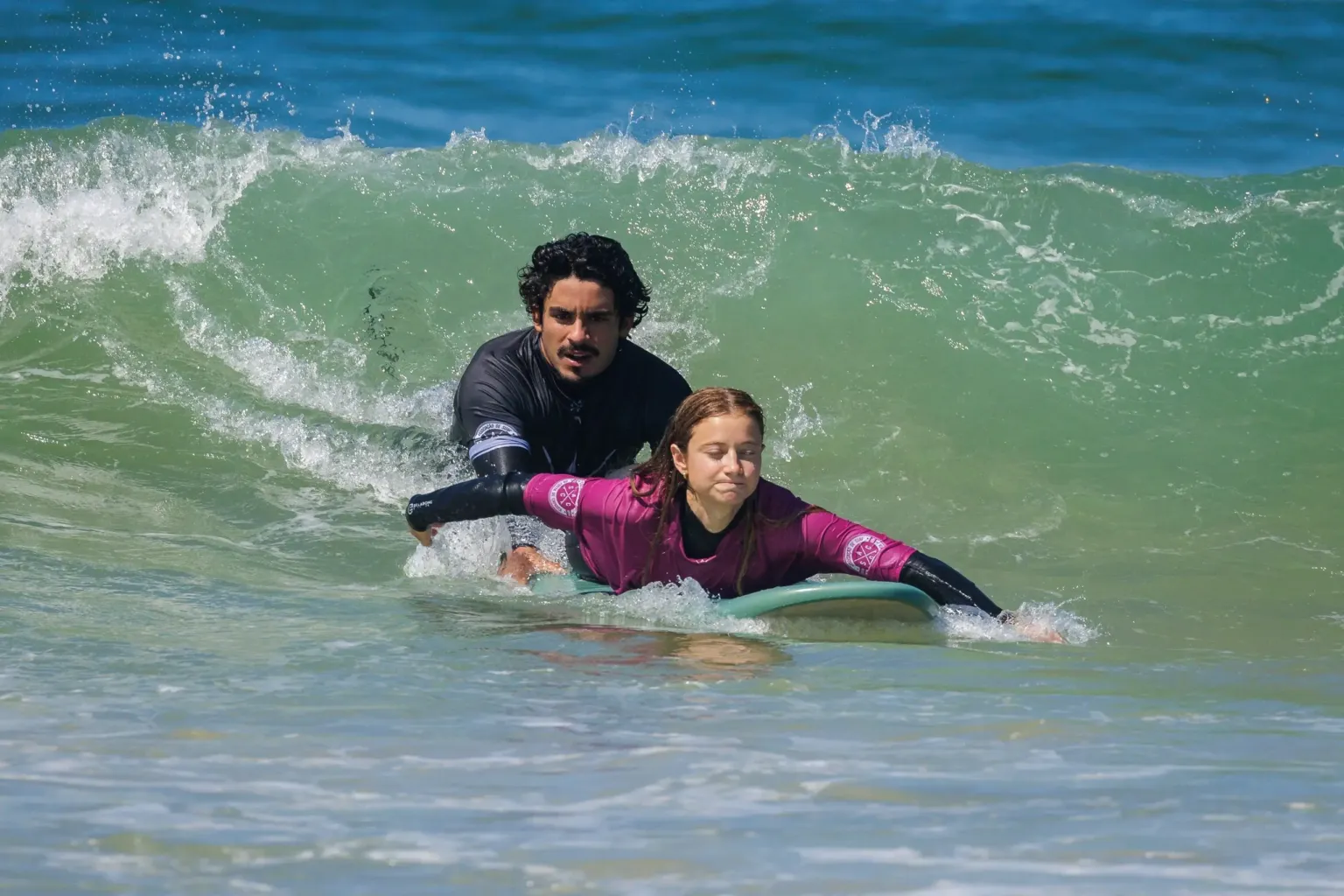 Instructor helping a student to paddle onto a wave