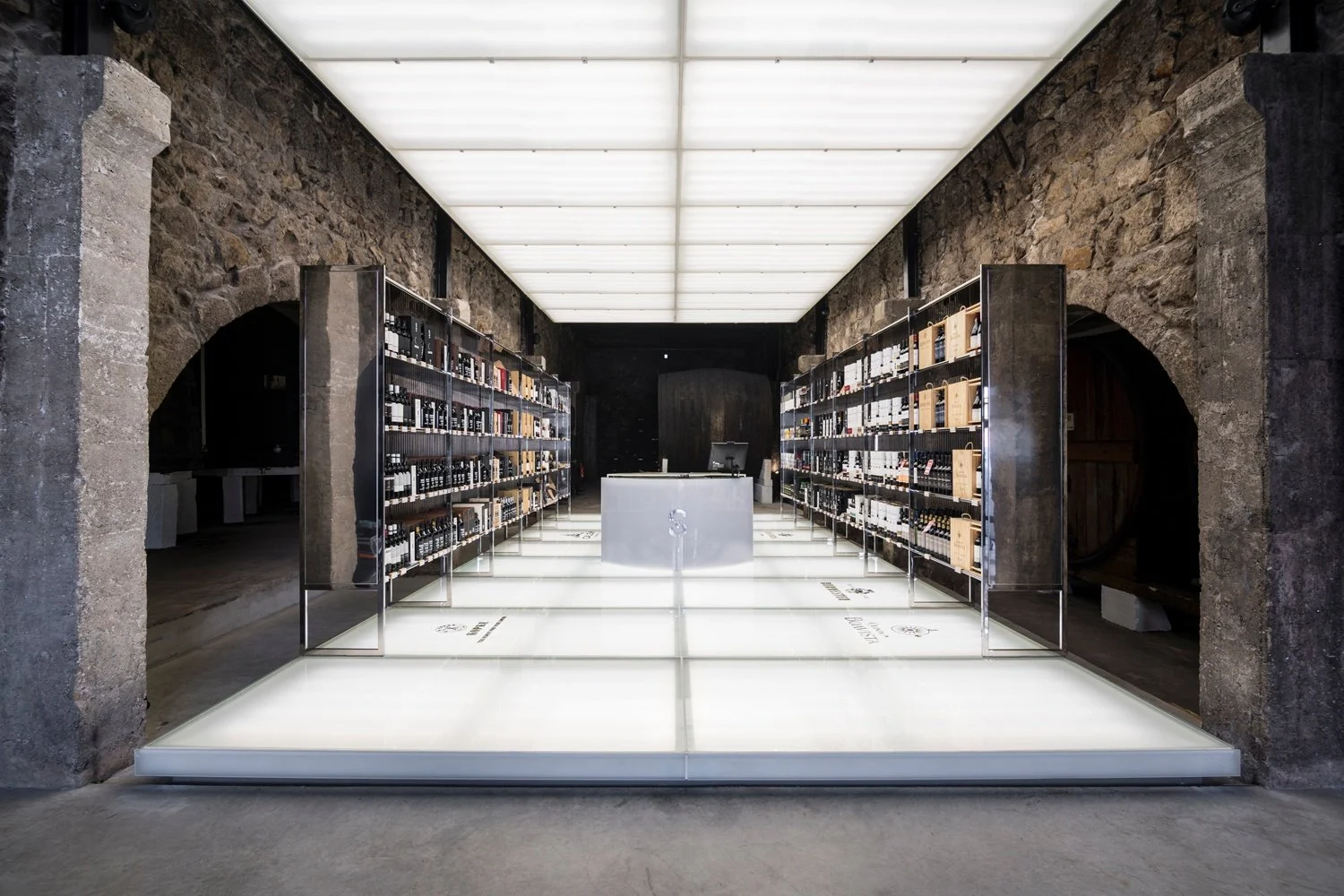Dark tasting hall with illuminated floor and wine shelves in stone cellars
