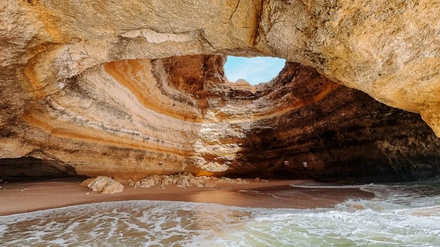 Sandstone sea cave with a round opening and a small beach