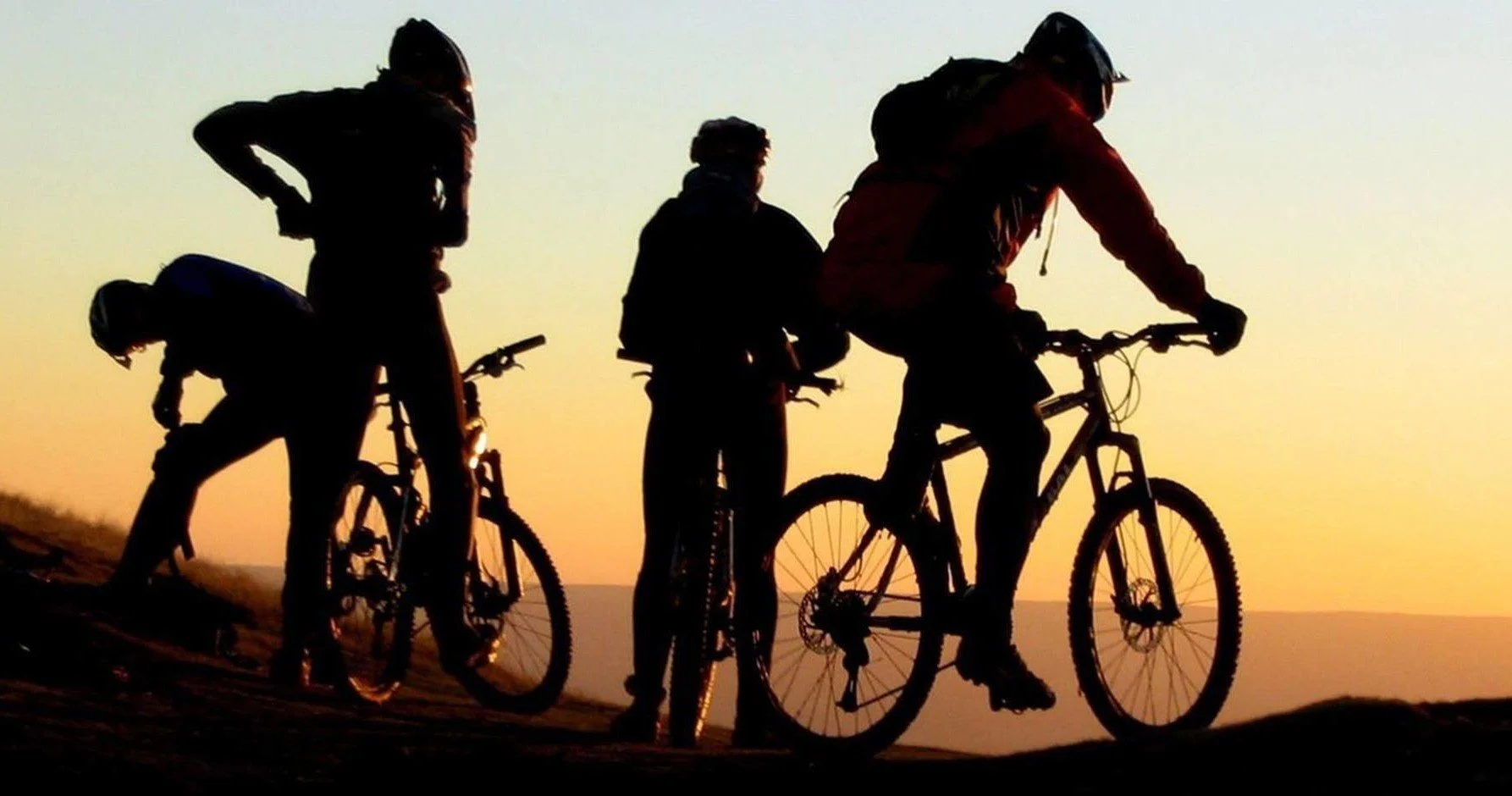 Silhouetted cyclists resting at sunset