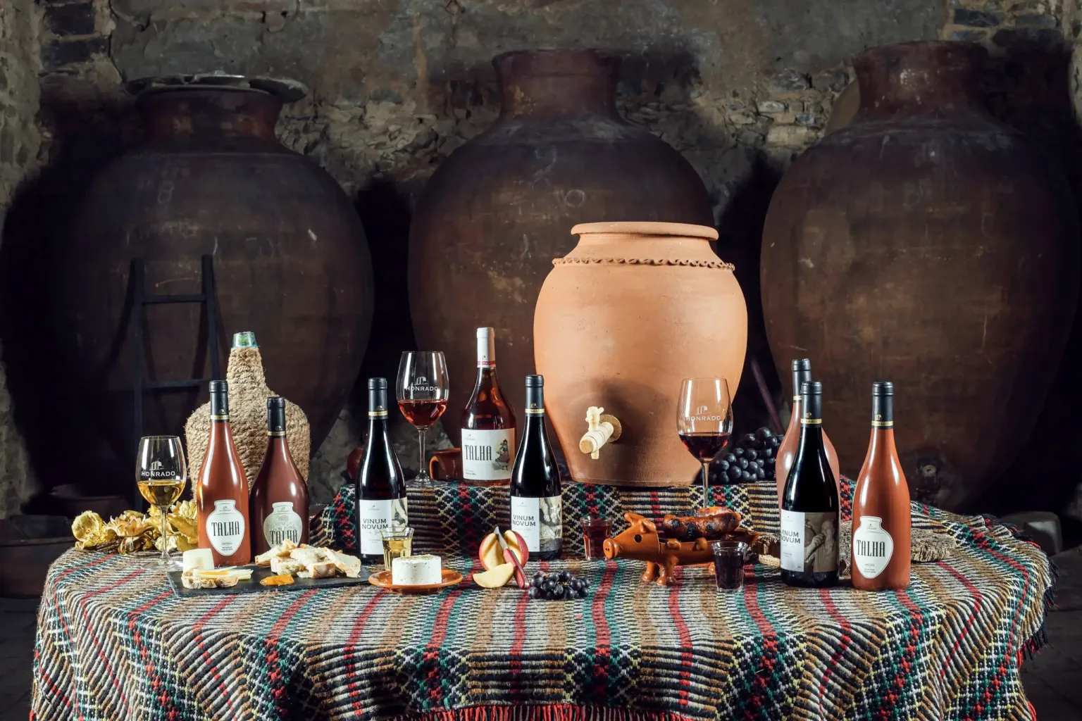 Table set with clay jars, wine bottles and regional foods