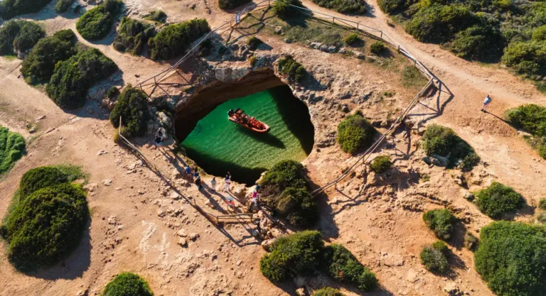 Aerial view of a small pond inside a collapsed cave opening on a clifftop