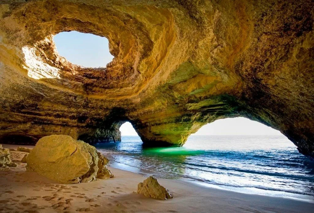 Sandstone sea cave with a round skylight and a small beach
