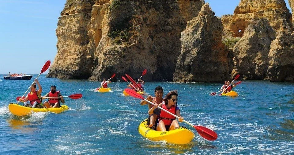 Kayakers paddling under sandstone sea stacks