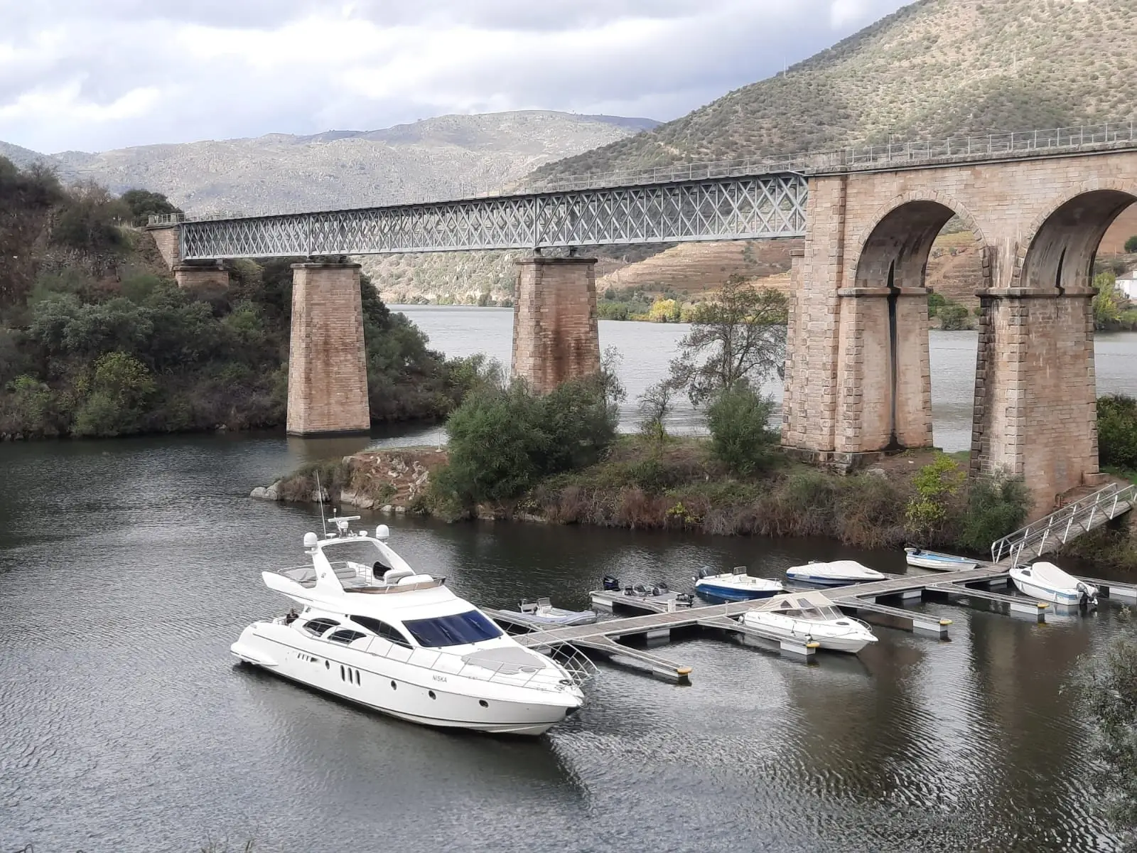 White yacht moored at a pontoon beside a railway viaduct