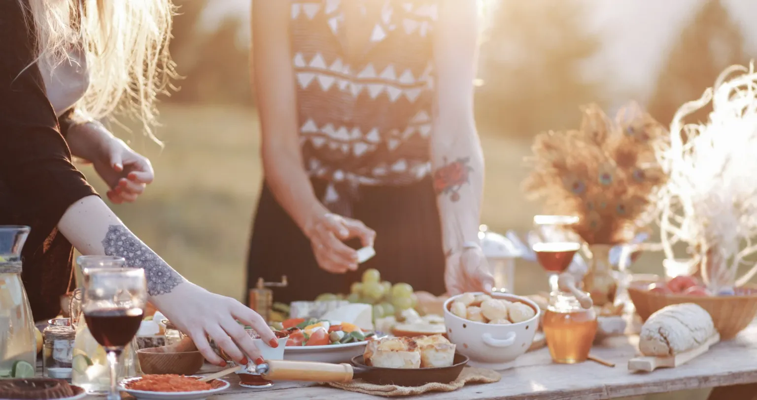 Guests laying out a picnic of cheese, fruit and wine outdoors
