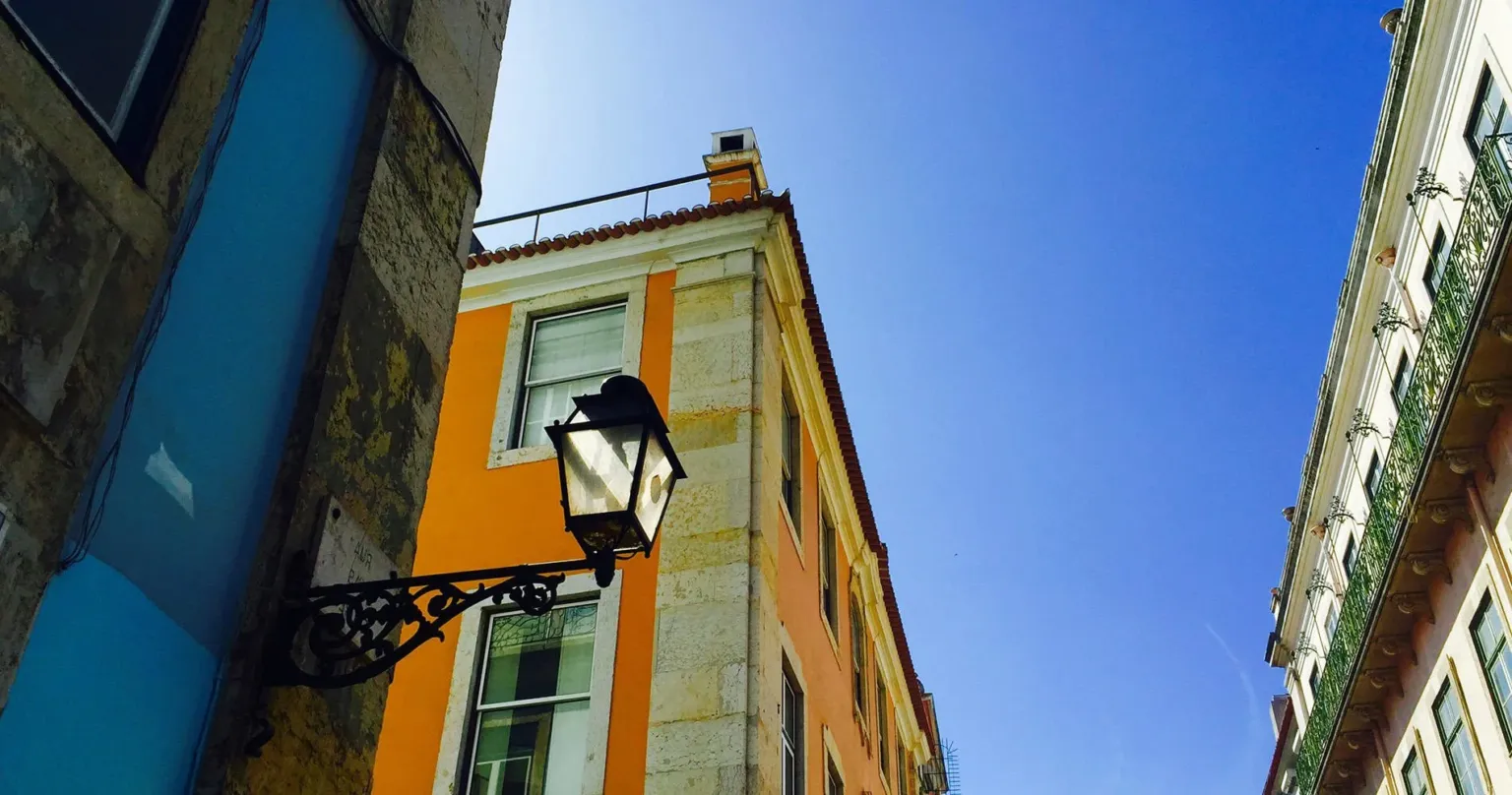 Orange building with a wrought-iron street lamp against a blue sky