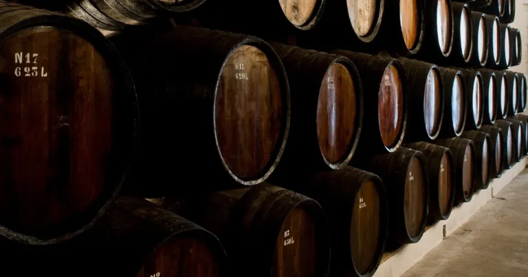 Rows of old wooden barrels in a dark cellar