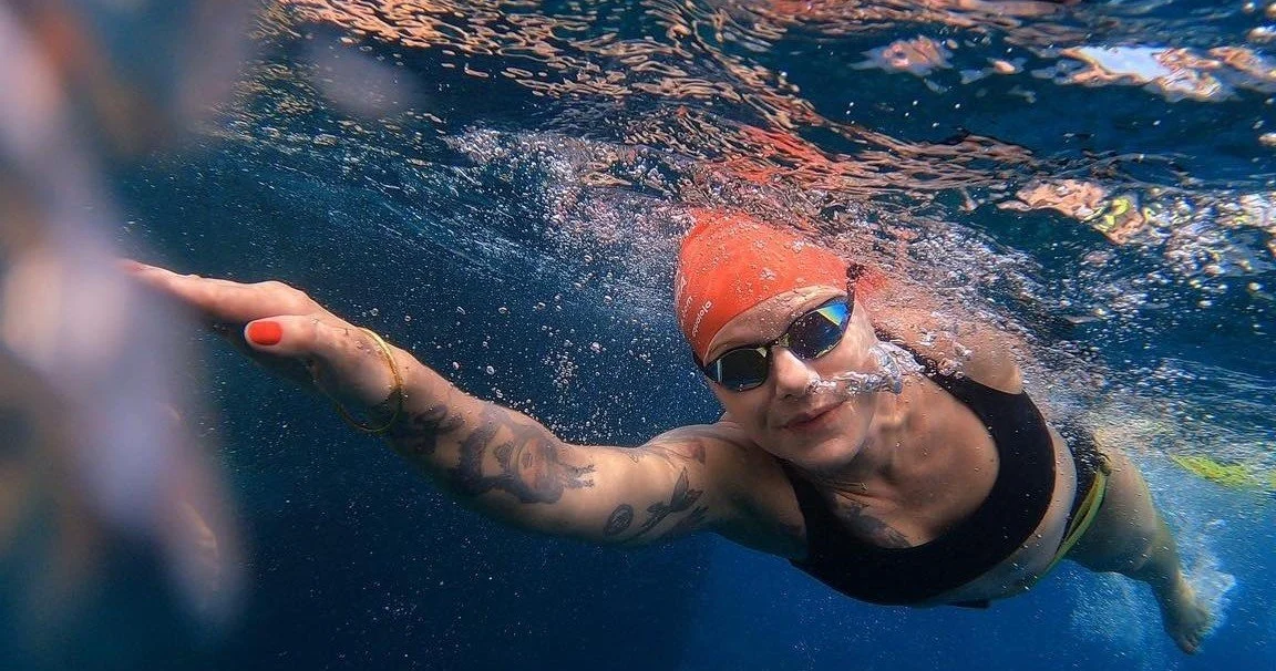 Swimmer in a red cap doing front crawl underwater