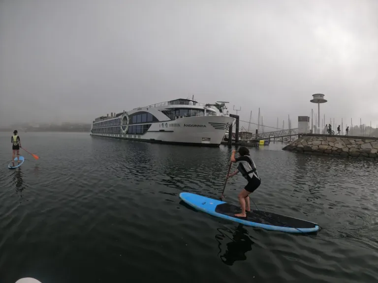 Paddleboarder on a misty river with a cruise ship moored behind