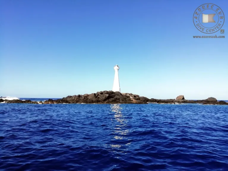 Small lighthouse on a rocky islet seen across deep blue water
