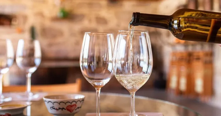 White wine being poured into a glass at a table