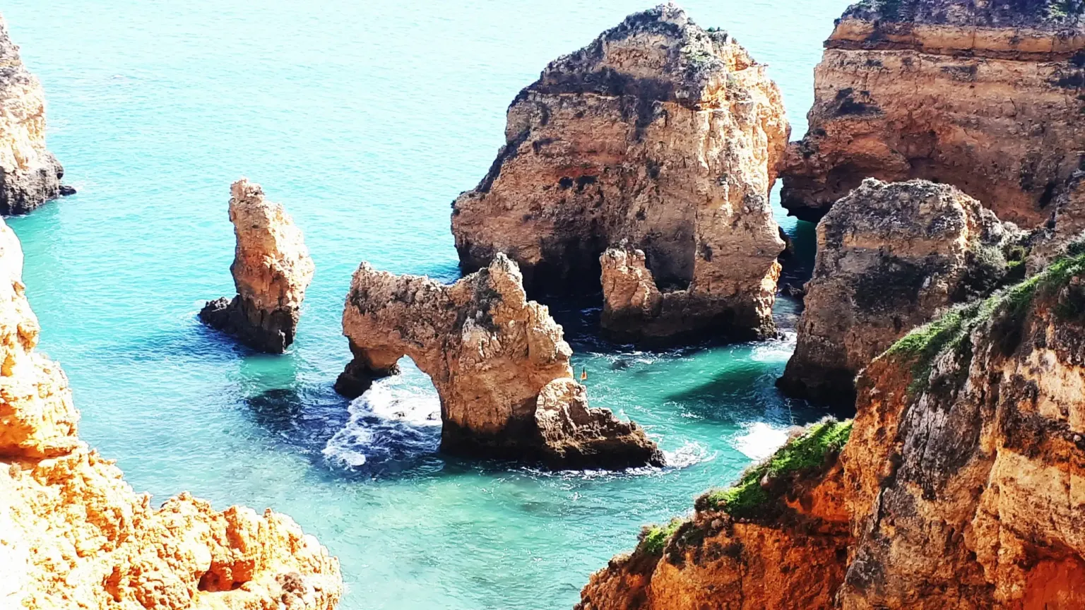 Golden rock arches and stacks rising from turquoise water