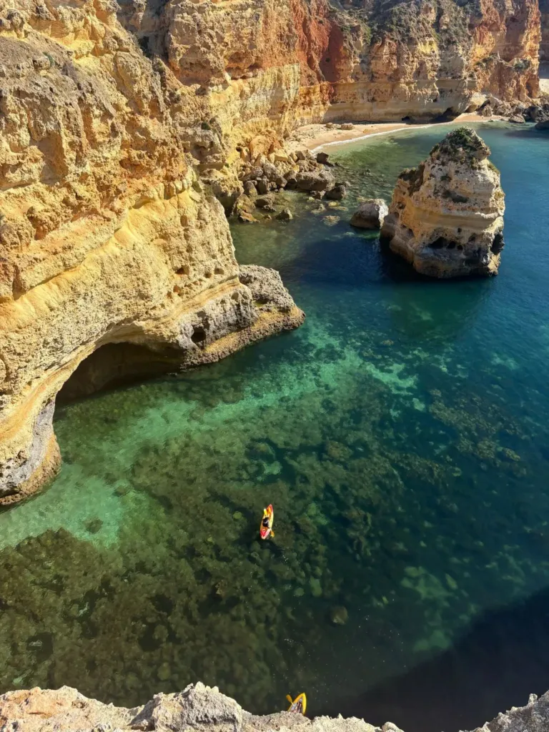 Aerial view of a rocky cove with a sea arch and turquoise water