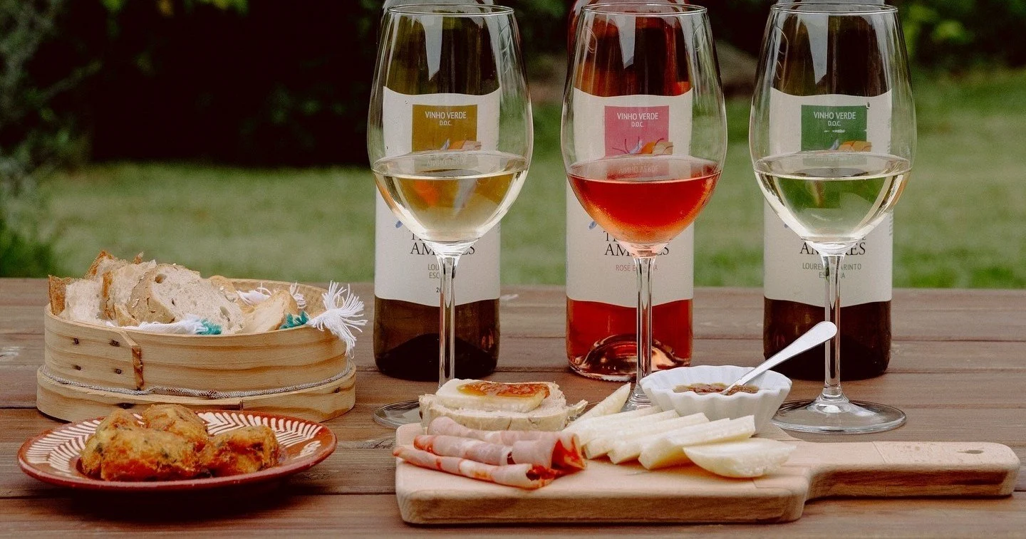 Three bottles of wine in different colours beside cheese and a snack platter