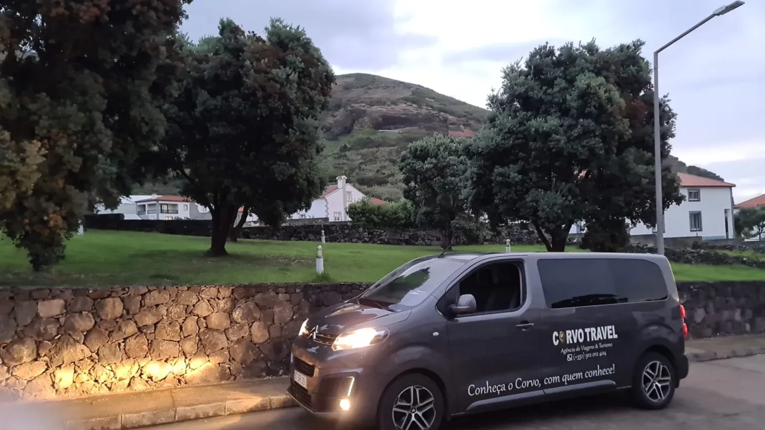 Dark minivan parked in a square at dusk