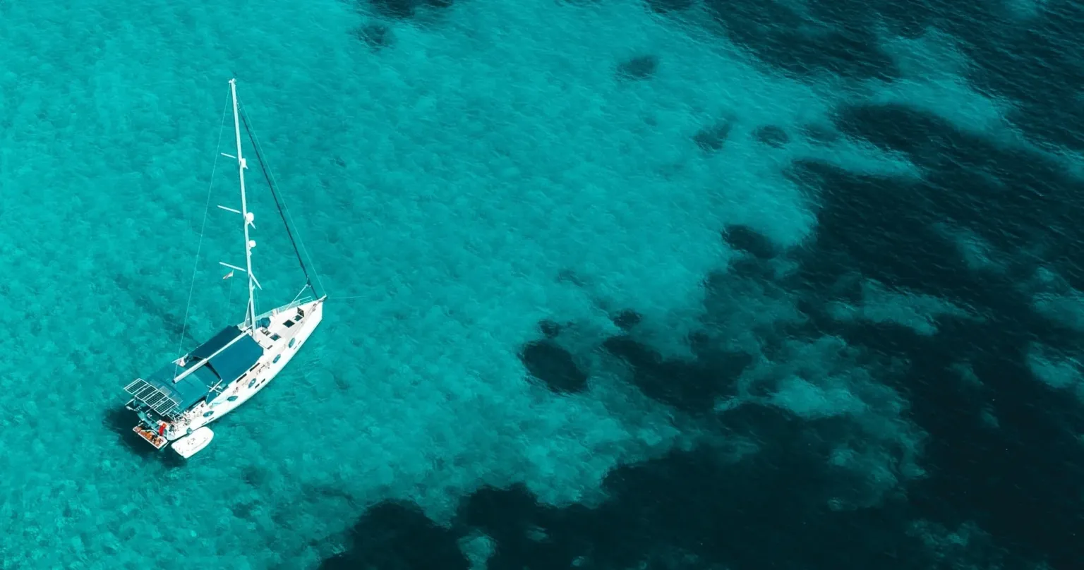 Aerial view of a sailing boat anchored over clear turquoise water