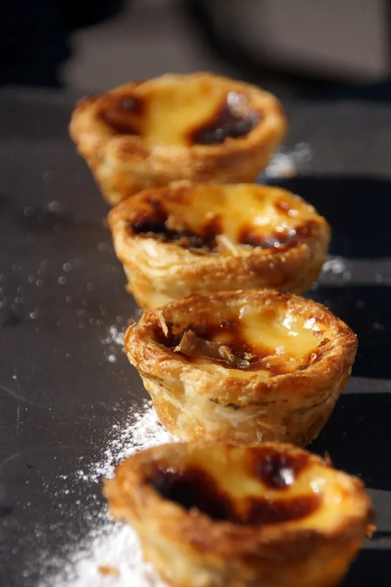 Stack of mini custard tarts on a dark surface