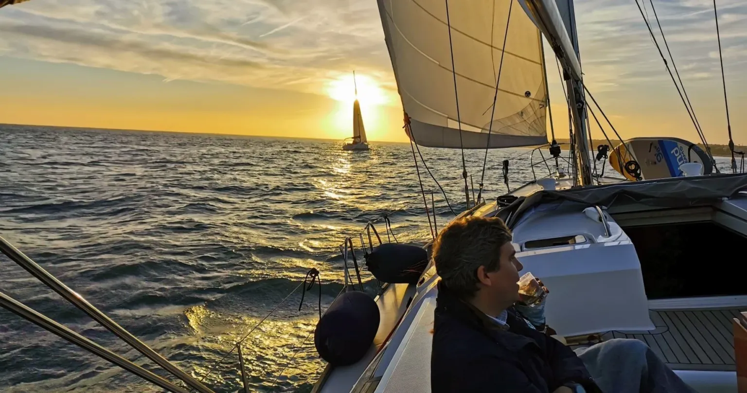 Man sitting at the stern of a sailboat at sunset