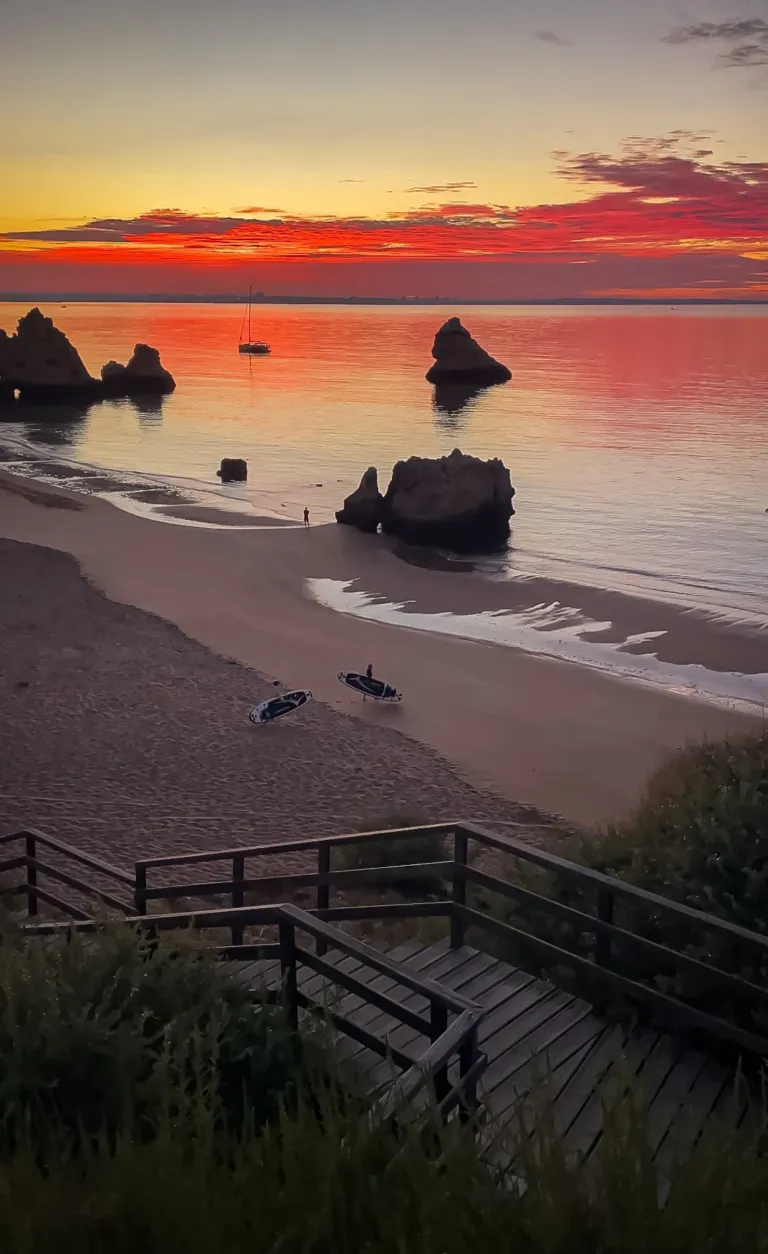 Beach at sunset with rock stacks and a wooden staircase down the cliff