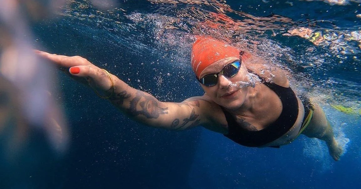 Swimmer in a red cap doing front crawl underwater