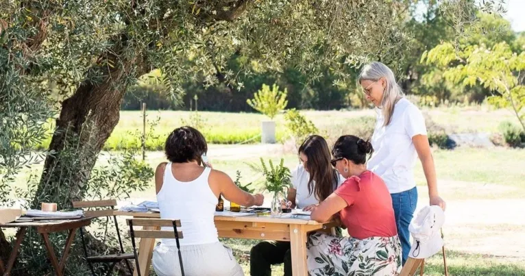 Group around a table painting botanical illustrations under an olive tree