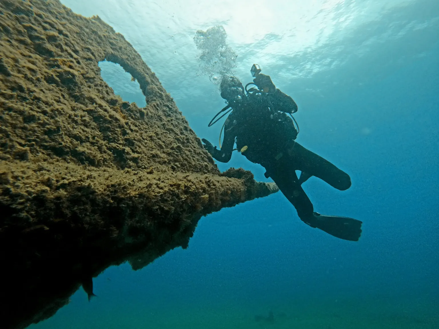 Diver swimming along the edge of a wreck