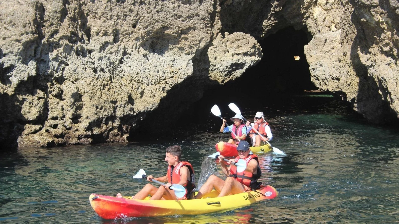Kayakers paddling into a sea cave entrance