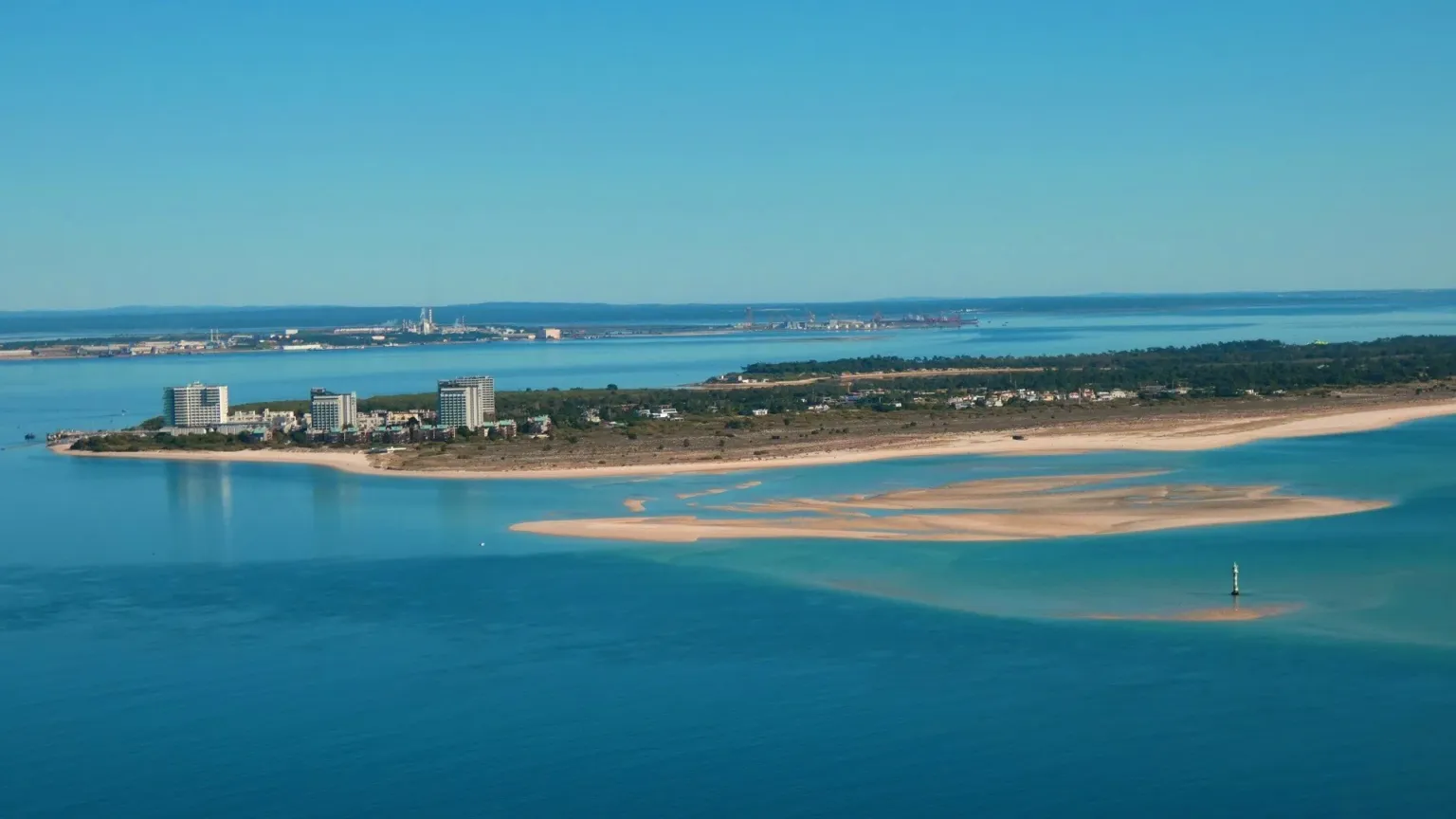 Aerial view of a sandy peninsula with apartment blocks and shallow banks