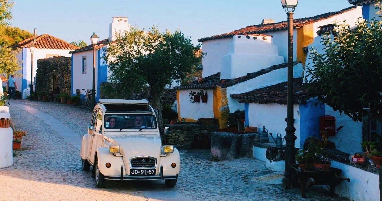 Cream vintage car parked in a whitewashed village street